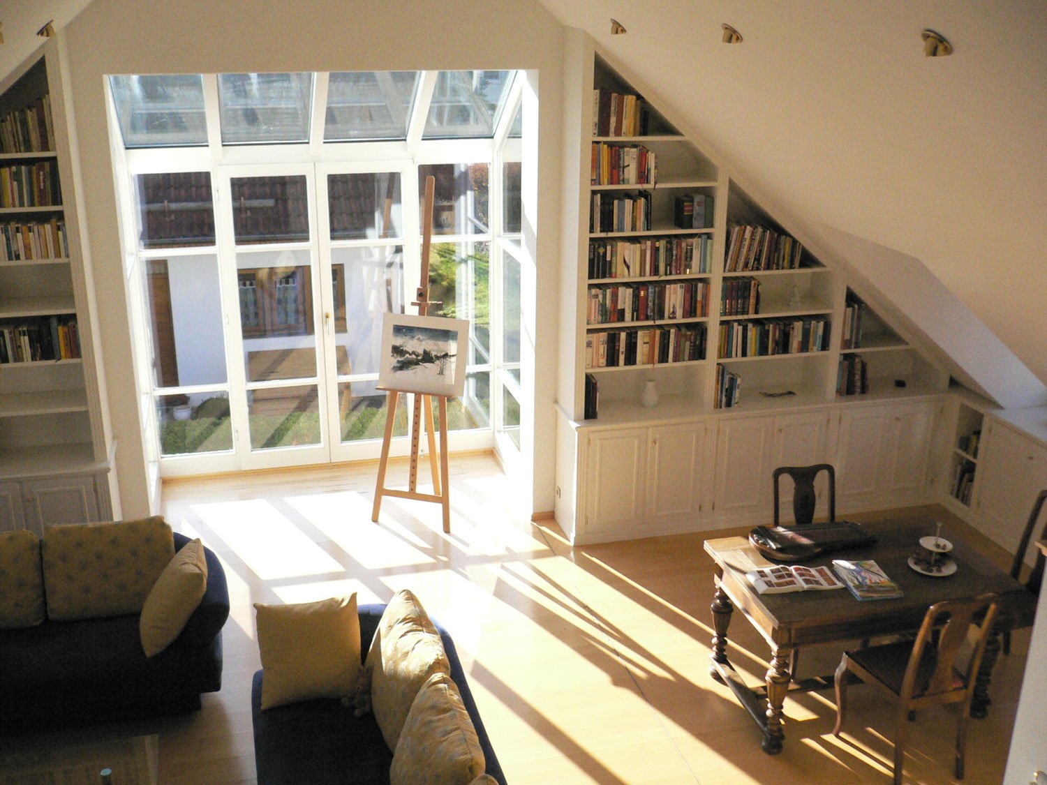 Ausgebautes Dachgeschoss mit Bücherregalen in der Schräge und großer Fensterfront