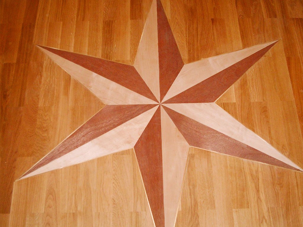 Holzparkett mit einem eingelegten Kompassstern aus hellem und rötlichem Holz