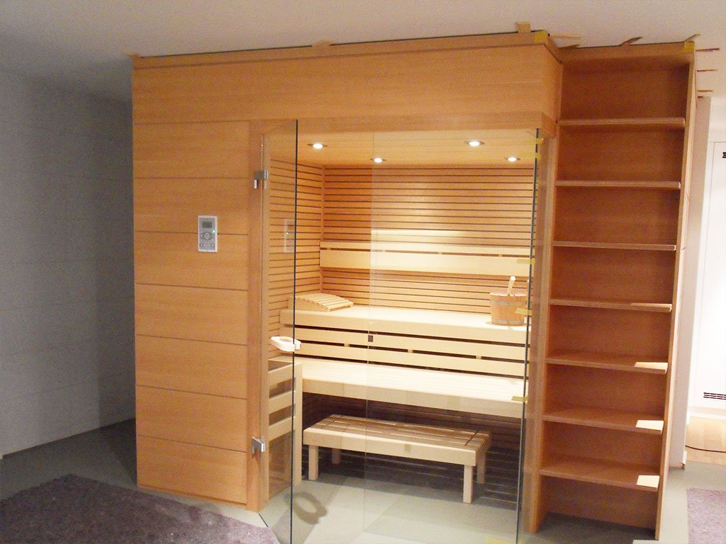Holzsauna mit Glastür, daneben ein offenes Regal aus demselben Holz